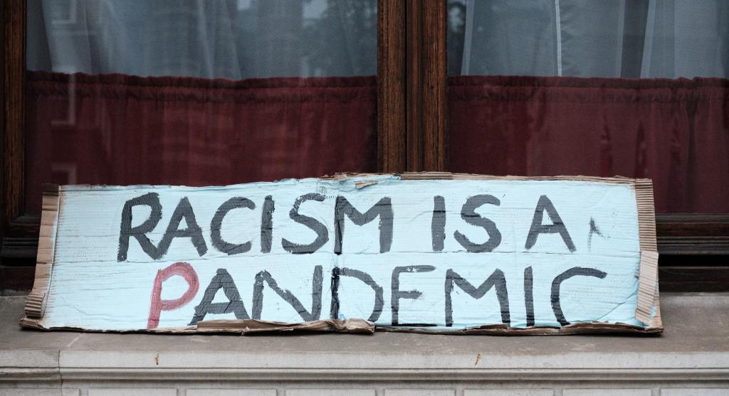 Protest sign reading RACISM IS A PANDEMIC