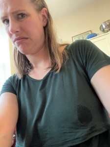 the author wearing a green dress with a wet spot over the breast, making a displeased expression